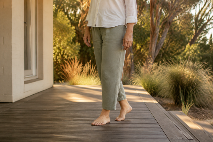 Barefoot woman taking an easy step along a timber verandah beside a native garden